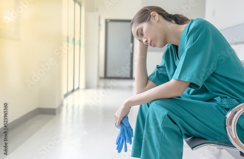 Young Asian doctor sitting on chair , feeling tired and depress after working, Hospital business