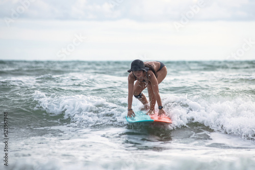 Woman surfer surfing and riding surfboard on the wave in the sea, surfing time, summer holidays travel
