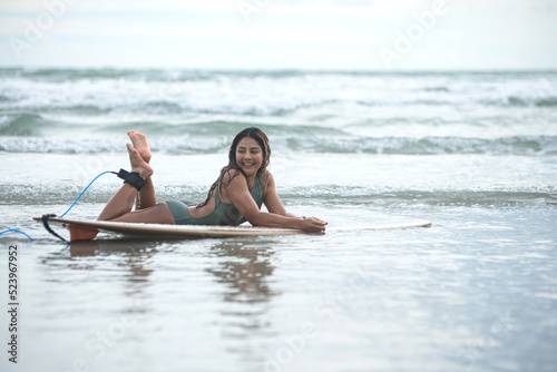Beautiful sexy asian surfer girl lying on surfboard on the beach,surfing time, summer holidays travel