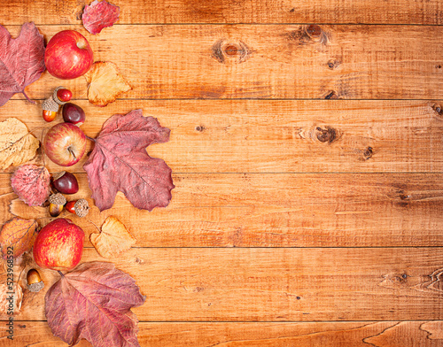 wooden table with composition of autumn leaves, acorns, apples with copy space