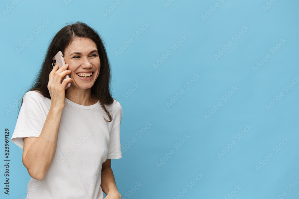 portrait of a nice, beautiful, pleasant woman in a white t-shirt talking on the phone smiling broadly portrait of a nice, beautiful, pleasant woman in a white t-shirt talking on the phone smiling broadly