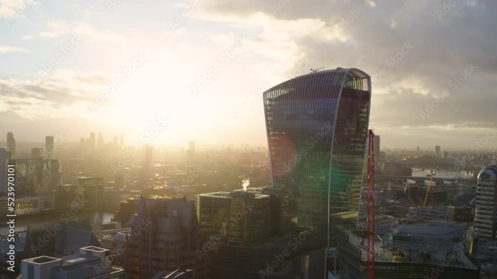 Cinematic panning aerial shot of the London financial district backlit by the morning sun featuring the iconic skyscrapers The Shard, The Walkie Talkie and The Scalpel