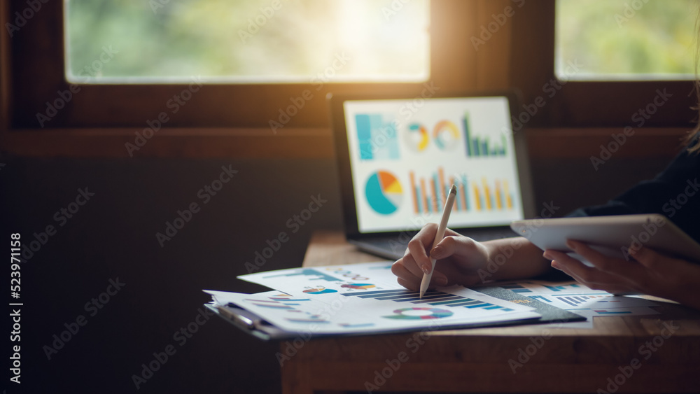 A businesswoman using a notebook and smartphone summarizes her company's profits with successful graphs. Check the results of the quarterly report using a notebook. A businesswoman using a notebook and smartphone summarizes her company's profits with successful graphs. Check the results of the quarterly report using a notebook.