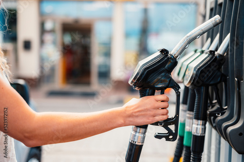 Photography Closeup of woman pumping gasoline fuel in car at gas station
