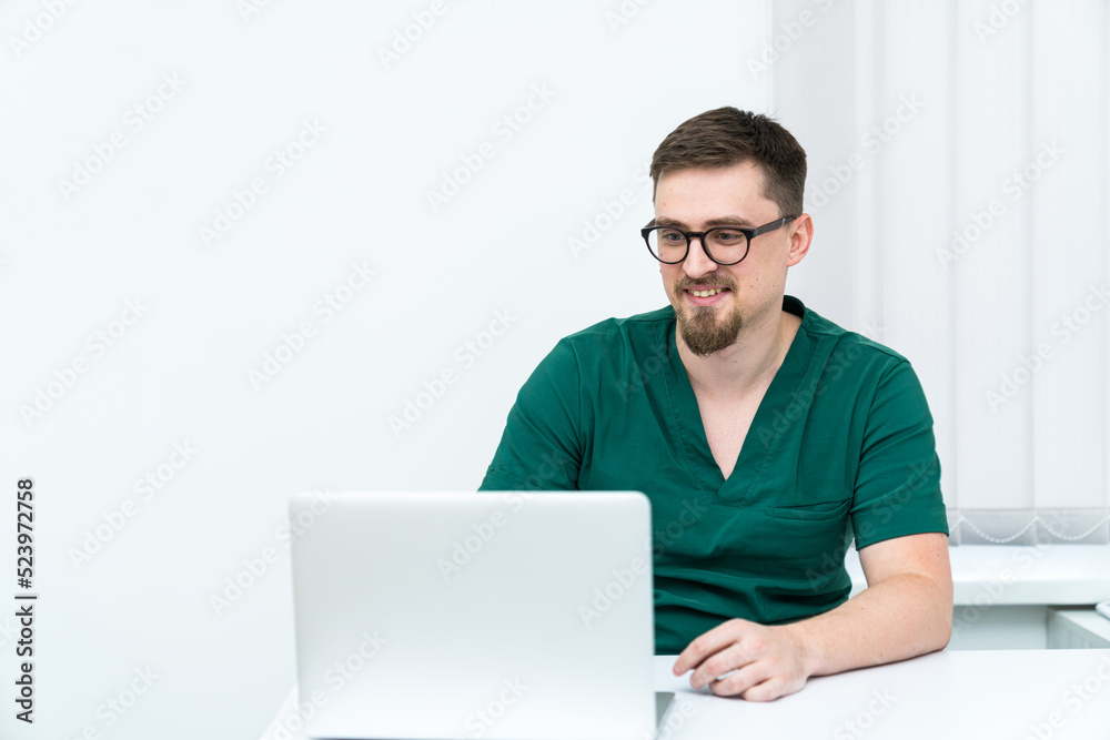 Young clinical specialist working with computer. Handsome physician sitting in the office. Young clinical specialist working with computer. Handsome physician sitting in the office.