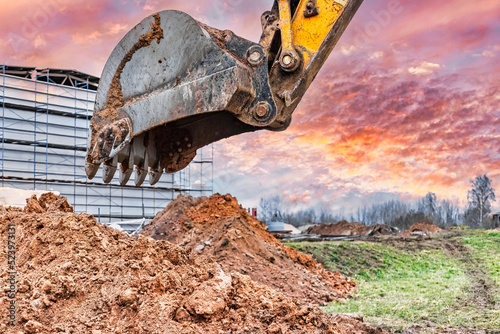 Close up of excavator bucket at construction site. The excavator is digging a trench for underground utilities. Construction equipment for earthworks.