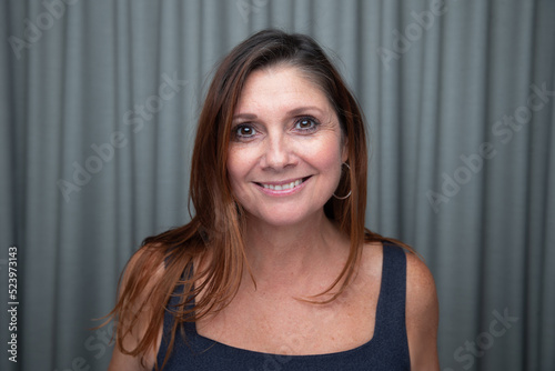 Beautiful middle aged woman smiling looking at you making eye contact in a head shot