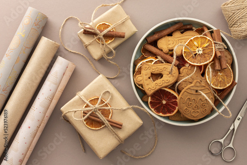 Preparing to decorate your home for Christmas, gift paper and dry citrus fruits with gingerbread cookies on a pastel powdery background