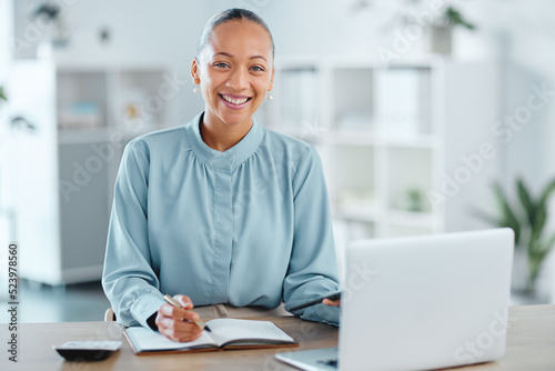 Modern, smiling and young business woman enjoying her work in a office at a computer indoors. Portrait of a happy junior corporate lawyer working, making notes and planning a successful job strategy photo
