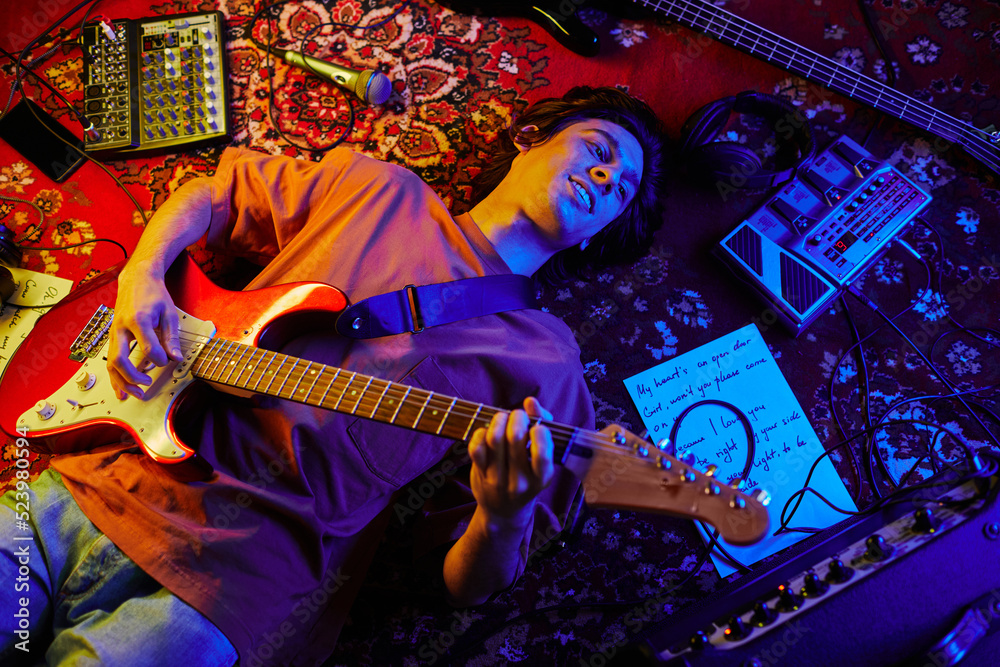 Ταπετσαρία Top view shot of young musician playing guitar while lying on carpet lit by neon