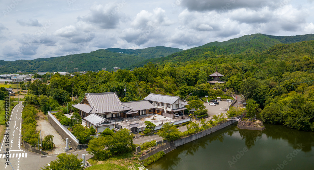 Naklejka premium Aerial view of traditional Japanese building between forest and road on sunny day