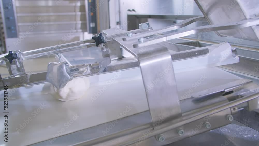 Dough pieces on the working conveyor line of dough machine in a bakery Dough pieces on the working conveyor line of dough machine in a bakery