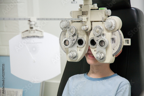 Young boy at an optometrist appointment looking through phoropter photo