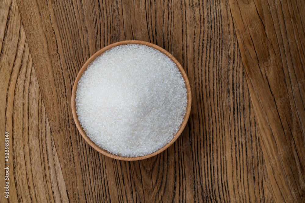 Granulated sugar in a bowl on wooden table Granulated sugar in a bowl on wooden table