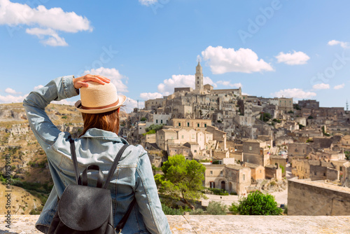 tourist girl with hat  looking the stunning view of the Sassi di Matera in Italy on a warm summer day. Travel destination, adventure, success and exploration concept. photo