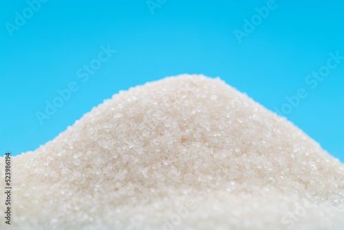 Pile of white sugar crystals on blue background