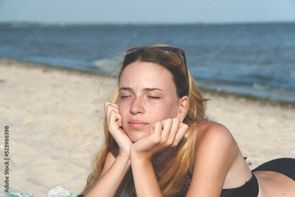 Peaceful facial expression of a girl on the seashore against the blue sky.