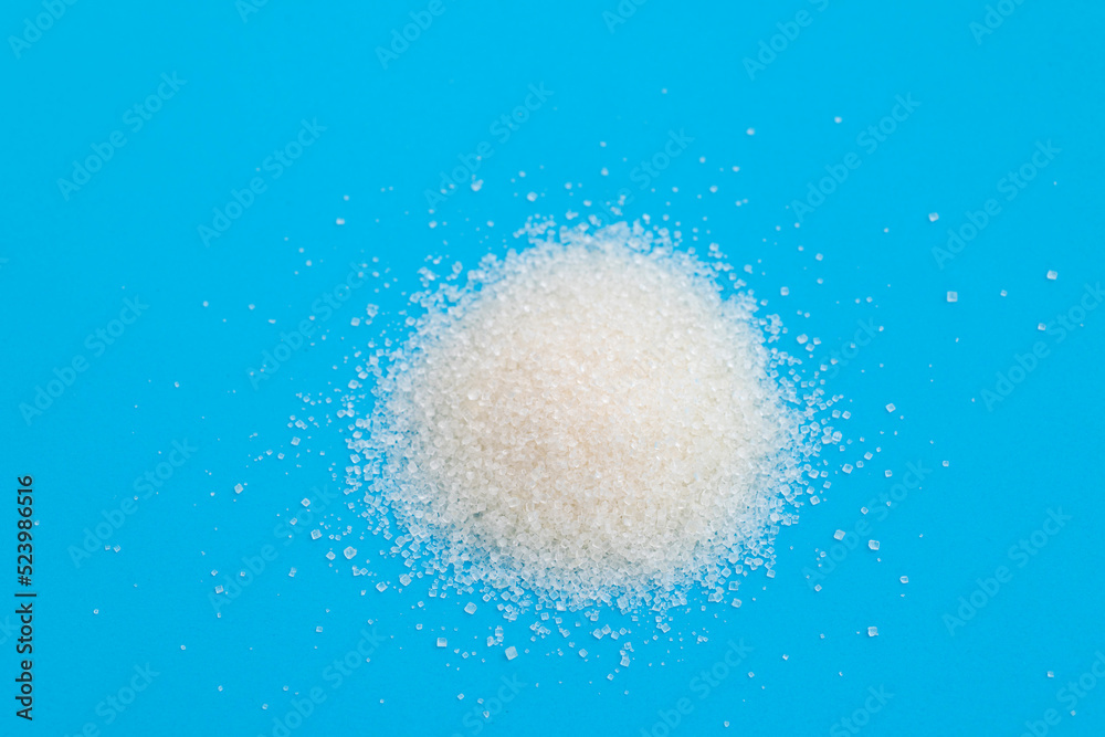 Pile of white sugar crystals on blue background Pile of white sugar crystals on blue background