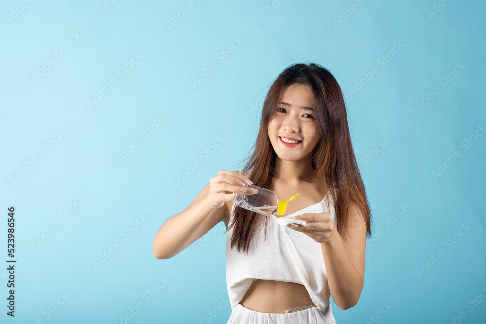 Facial Beauty Treatment Hygiene Skin. Happy Asian beautiful young woman drop removing cosmetic make up water to pad cotton face cleaner disc for cleaning, studio shot isolated on blue background Facial Beauty Treatment Hygiene Skin. Happy Asian beautiful young woman drop removing cosmetic make up water to pad cotton face cleaner disc for cleaning, studio shot isolated on blue background