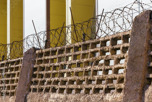 Barbed wire stretches along the wall. Concrete wall with barbed wire. Protected area. Danger zone.