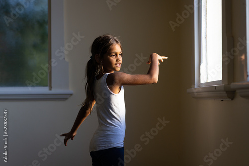 little aboriginal girl dancing by herself in bare room photo