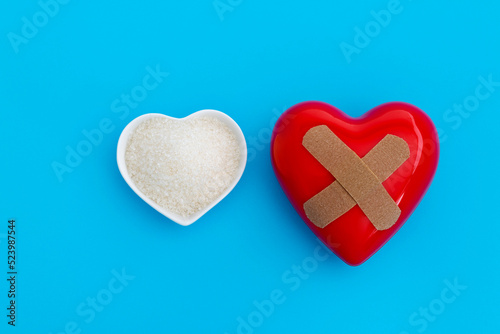 Red heart with bandage and a bowl of granulated sugar