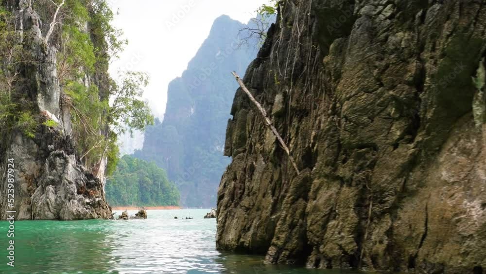 Siling fast past a rock formation in a longtail boat in Cheow Lan Lake surrounded by jungle in Khao Sok National Park In Thailand Siling fast past a rock formation in a longtail boat in Cheow Lan Lake surrounded by jungle in Khao Sok National Park In Thailand