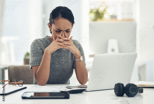 Stress, anxiety and worry with a businesswoman feeling negative, overworked and overwhelmed while suffering from a headache or migraine. Young female working on a laptop at her desk in the office