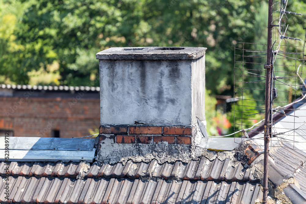 Fototapeta premium Chimney and antenna on the roof of old house on sunny day