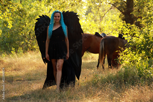 Woman with black wings walking outdoors © Сергей Луговский