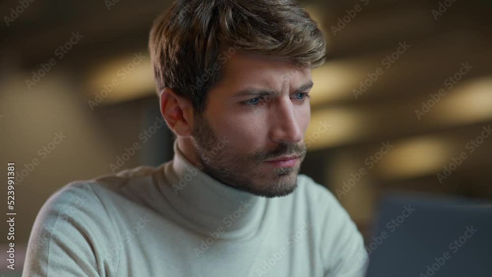 Handheld, portrait of a young manager working on a laptop, focused man working overtime, the thinking process. Handheld, portrait of a young manager working on a laptop, focused man working overtime, the thinking process.
