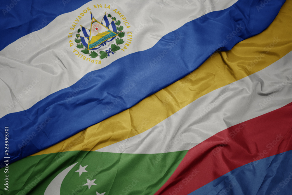 Fototapeta premium waving colorful flag of comoros and national flag of el salvador.