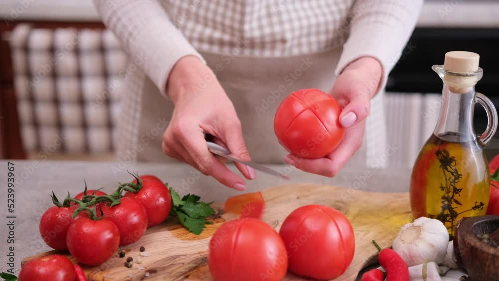 woman peels a tomato peel by knife at domestic kitchen woman peels a tomato peel by knife at domestic kitchen