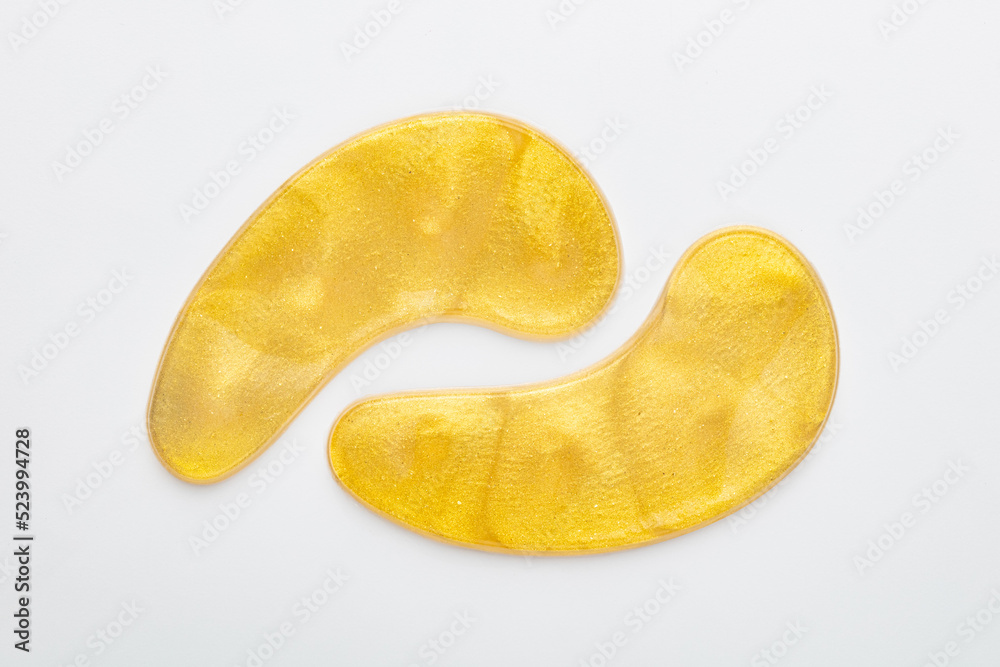 Gold hydrogel eye patches on white background.