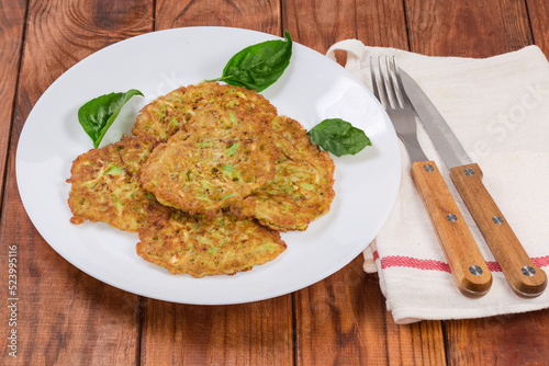 Serving of thick savory zucchini pancakes on old rustic table
