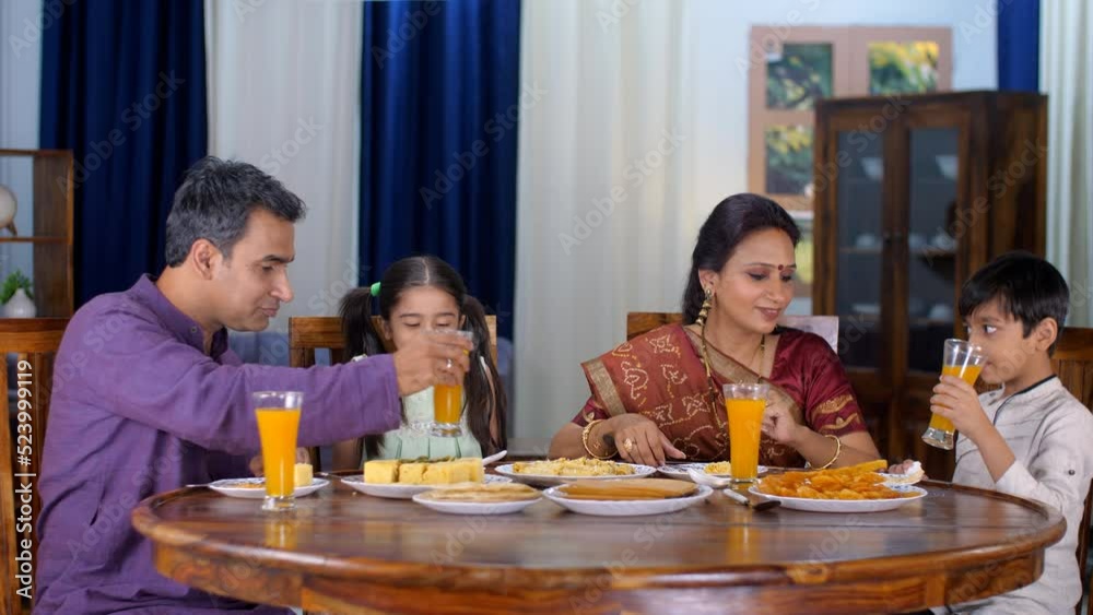 A happy Gujarati family husband wife and young kids having food