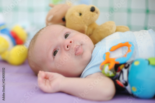Baby boy with many colorful plastic toy and rattle around head. Close-up detail portrait. Love and family emotion