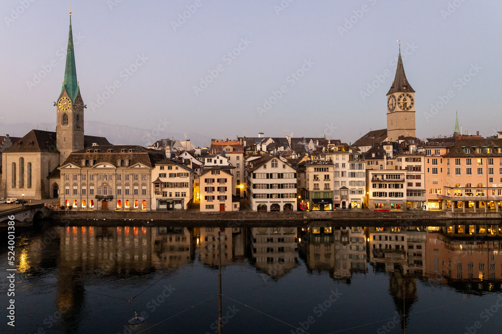 Blick auf die Altstadt von Zürich über der Limmat, früher Morgen, Lichter im Spiegel des Wassers