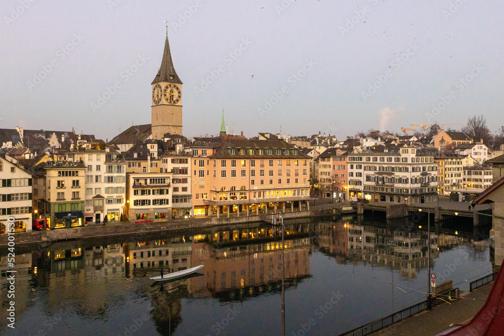 Blick auf den Fluss Limmat in Zürich, früher Morgen, rotes Licht, Spiegelungen im Wasser, ein Boot in der Stille des Morgens