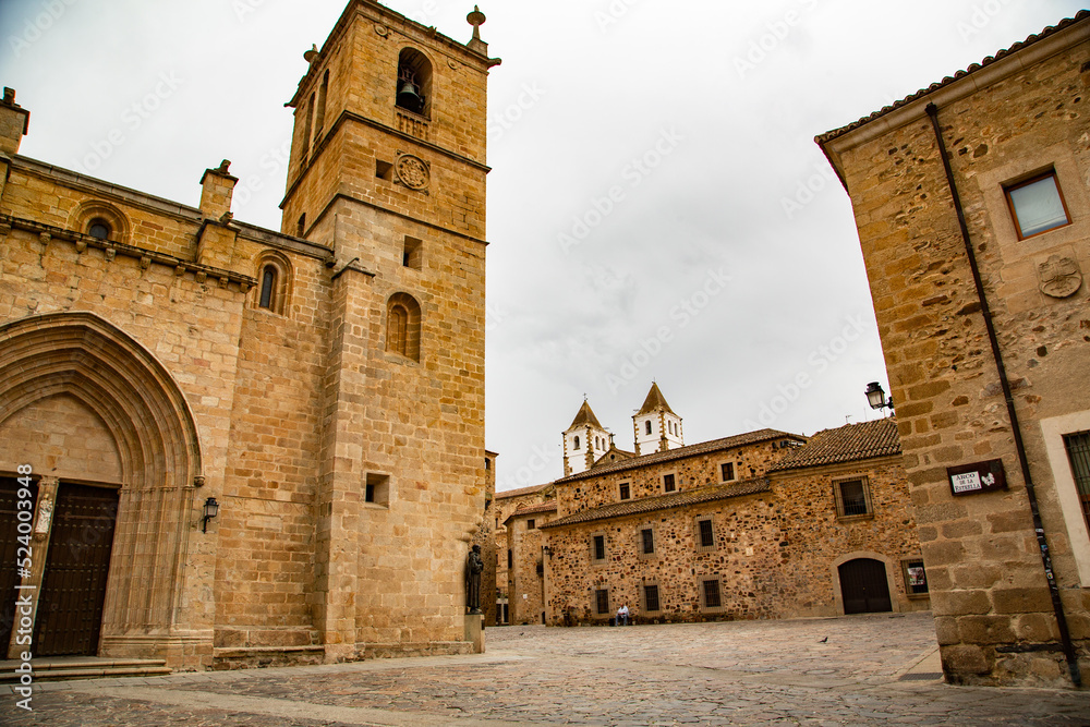 Iglesia de piedra beige con portada románica y torre de campanario anexa
