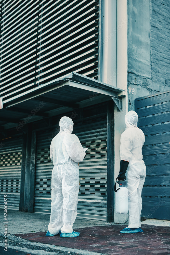 Medical team and covid hygiene healthcare workers wearing hazmat suits for safety while at quarantine site outside. In protective gear for cleaning, disinfection and decontamination to fight virus