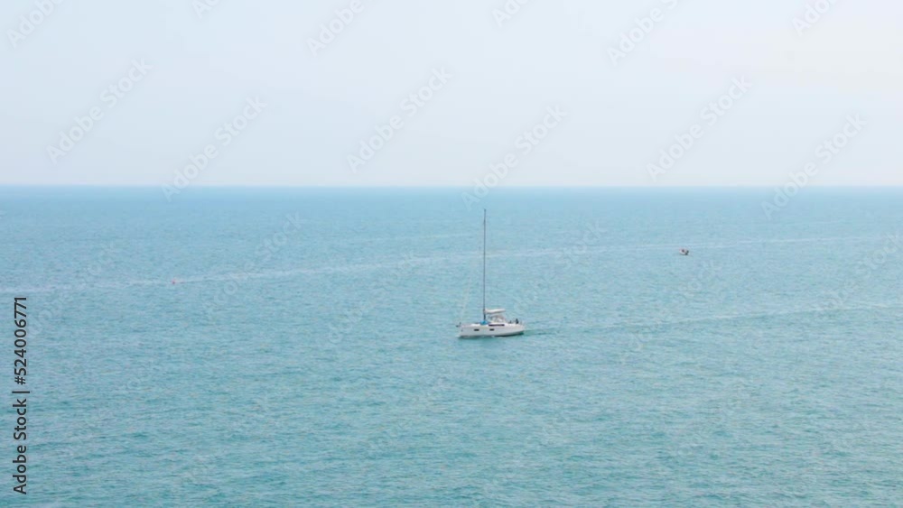 A sailboat is sailing in the distance. Beautiful summer seascape. Travel and tourism concept A sailboat is sailing in the distance. Beautiful summer seascape. Travel and tourism concept