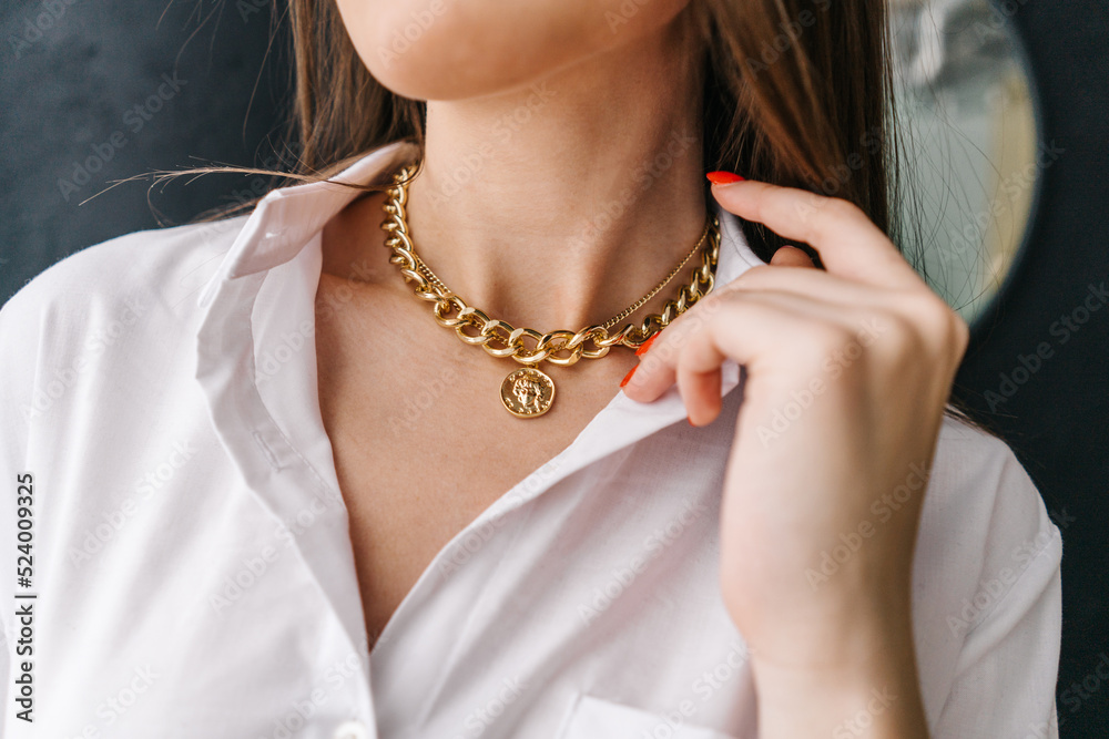 Golden bijouterie chain on woman neck. Close-up.