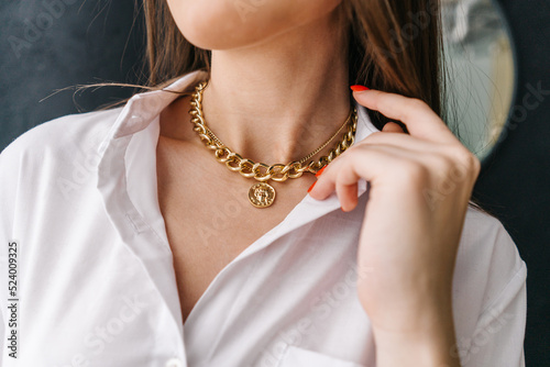 Golden bijouterie chain on woman neck. Close-up.