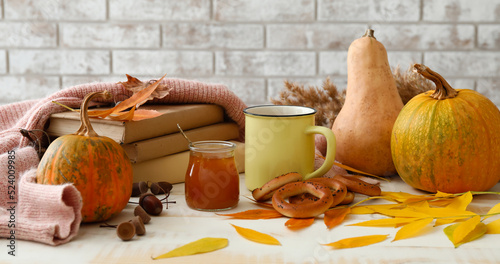 Autumn composition with books, cup of aromatic tea, jar of tasty jam and cracknels on table photo