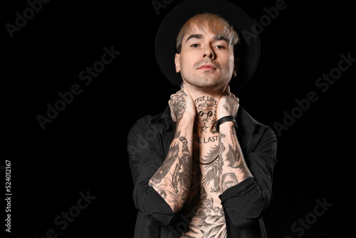 Young tattooed man on black...