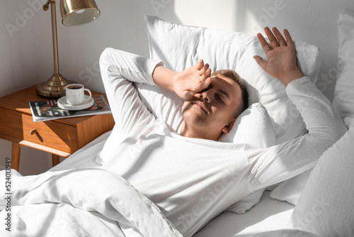 Young man waking up at home...
