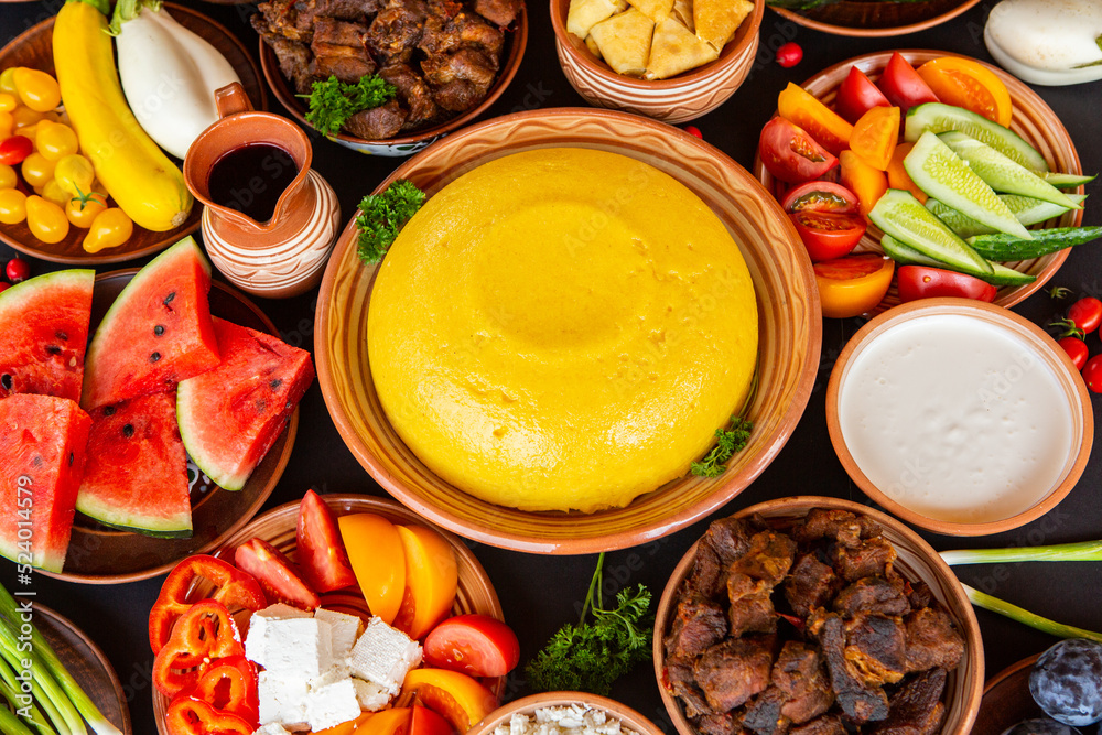 Homemade Romanian Food with polenta, meat, cheese and vegetables. Delicious corn porridge in clay dishes. Mamaliga or polenta, a traditional dish in Moldova, Hungary and Ukrainian cuisine.
