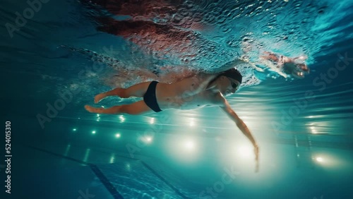 Professional swimmer athlete swims underwater in the pool