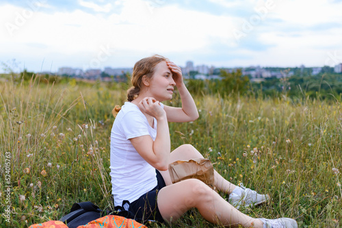A redhead woman is resting on a hill and preparing for a picnic